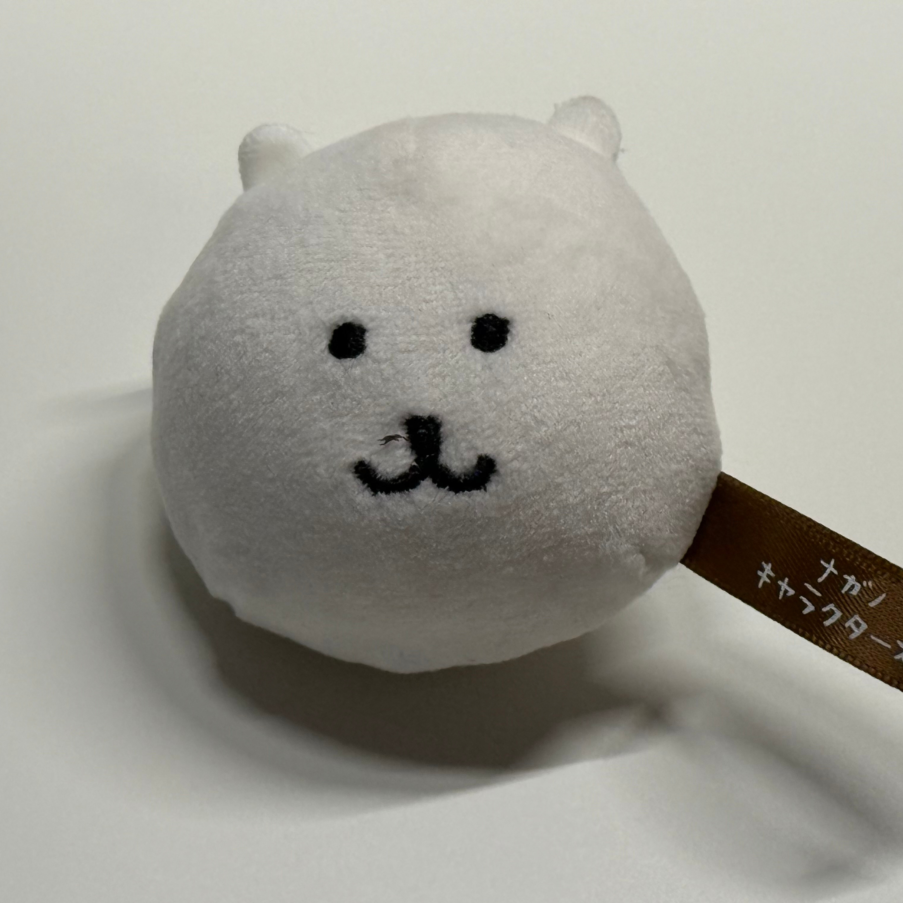 Front view of the plush toy with face and tag